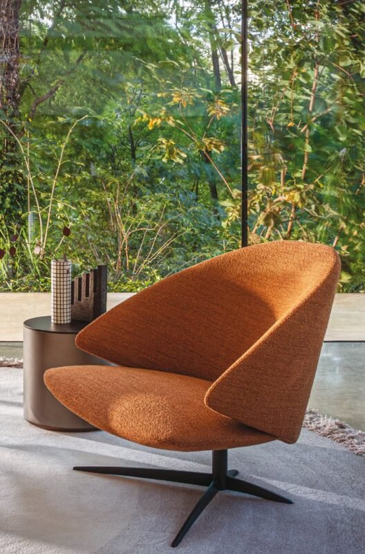 Désirée armchair in orange by a garden window